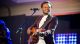 Travis Greene plays the guitar on stage.