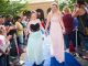 Two girls walk the blue carpet in their prom dresses.