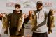Two Dick Hiley Bass Classic participants hold up their catches and smile at weigh-in. 