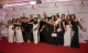 The St. Jude Orlando Gala committee poses on the red carpet wearing white and black gowns and suits. 