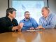 Three scientists sit at a conference table and discuss their research findings.